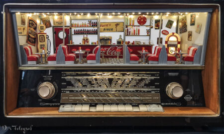 Bild zeigt ein altes Röhrenradio, in welchem statt des Lautsprechers über der Skala ein Miniaturrestaurant im 1950er Jahre US-Stil eingebaut ist