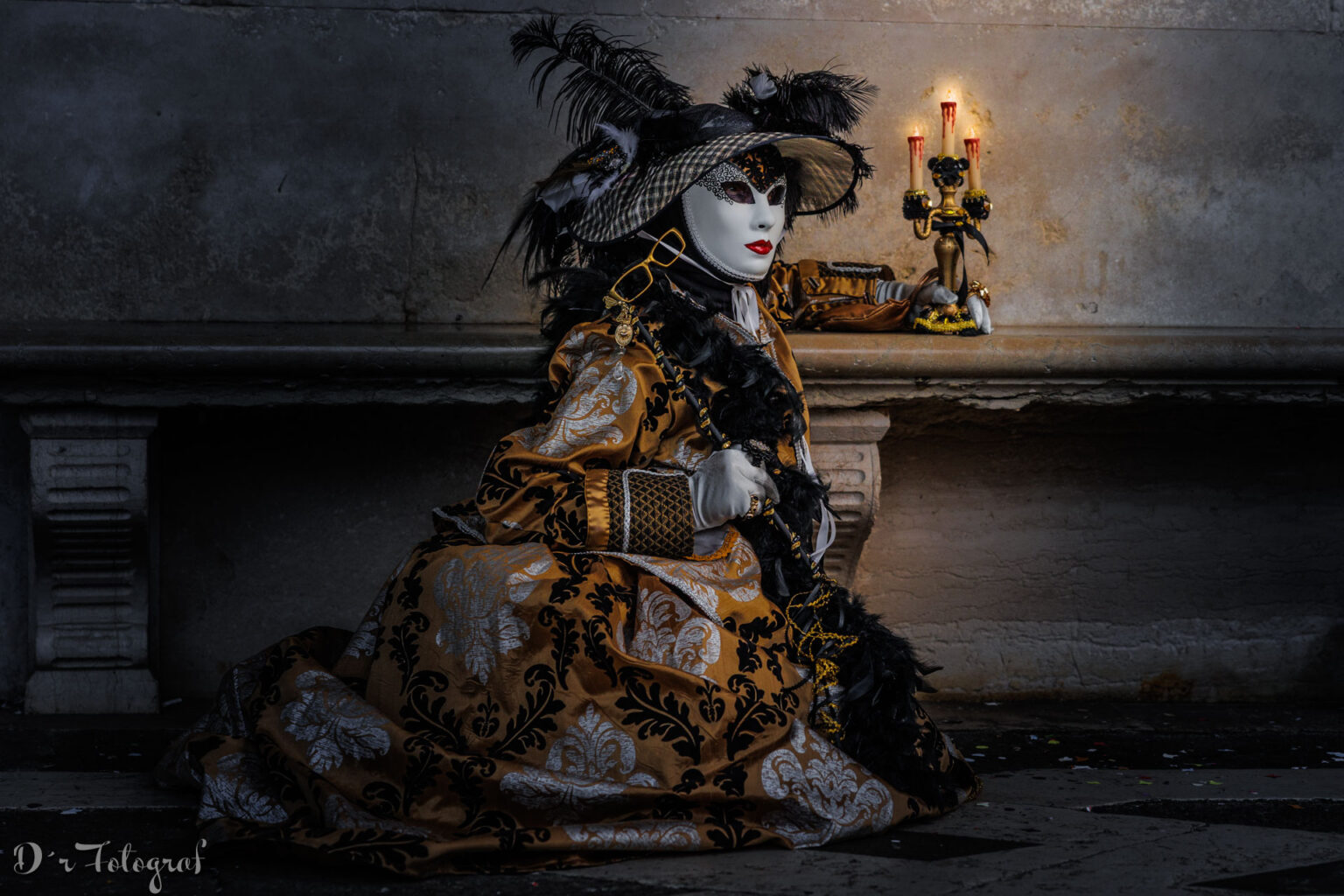 Venezianische Maske sitzend mit Kerzenständer. Kostüm in schwarz und gold